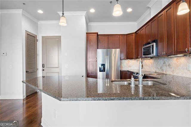 kitchen featuring ornamental molding, stainless steel appliances, hanging light fixtures, and dark stone counters