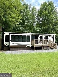 back of house featuring a lawn and a wooden deck