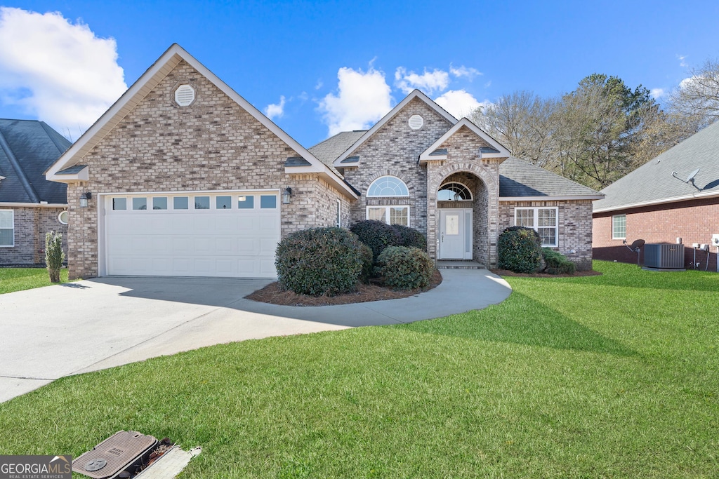 view of front of house with central AC, a front lawn, and a garage