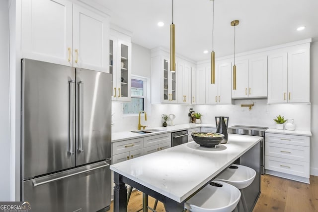 kitchen with stainless steel appliances, light countertops, glass insert cabinets, and white cabinetry