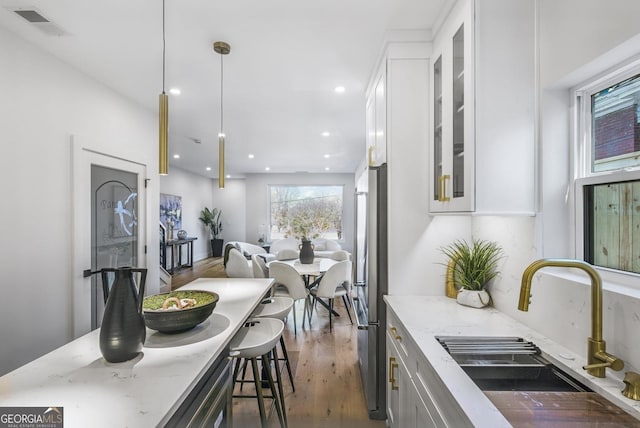 kitchen featuring open floor plan, a sink, decorative light fixtures, and white cabinets