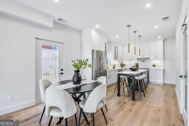 dining space with baseboards, light wood-style flooring, visible vents, and recessed lighting