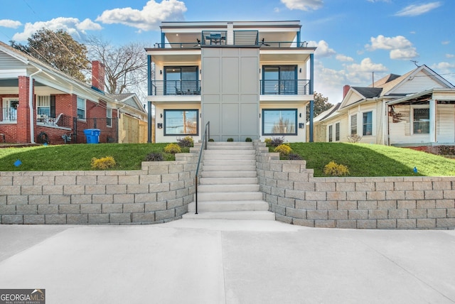 view of front facade featuring a balcony, stairs, and stucco siding