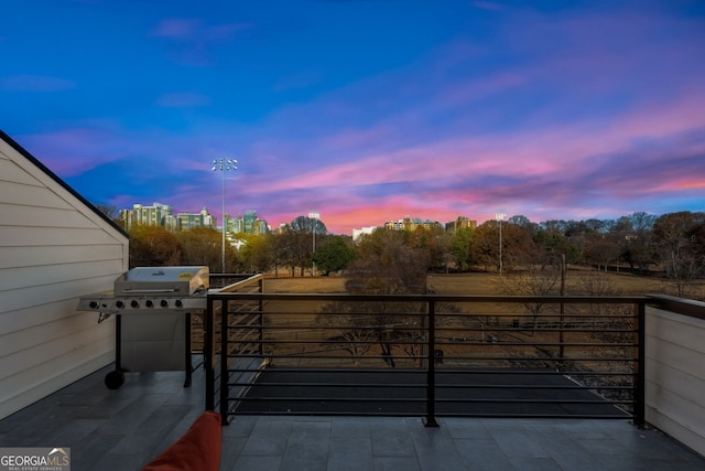 patio terrace at dusk featuring a balcony and grilling area