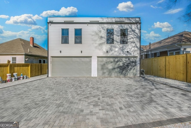 exterior space featuring decorative driveway, an attached garage, and fence