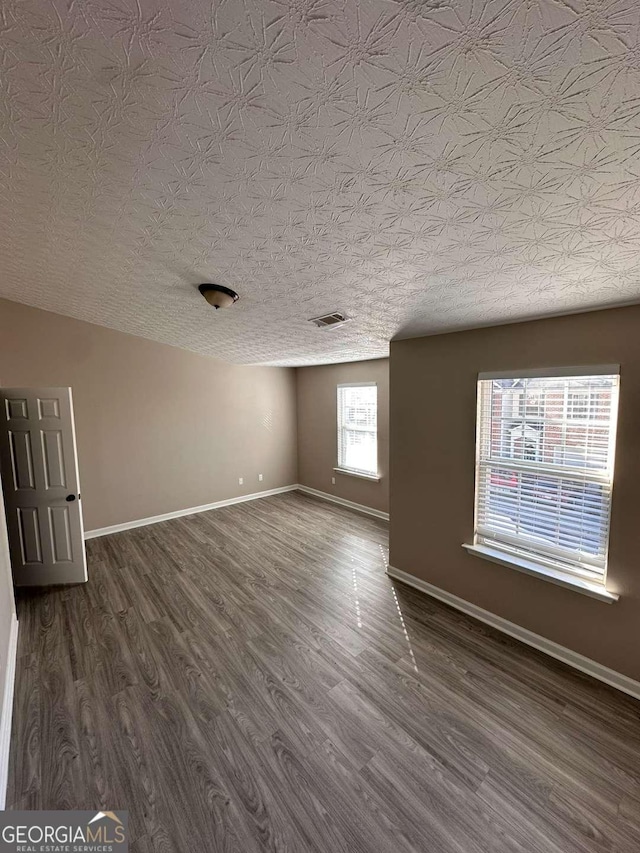 empty room featuring dark wood-type flooring and a textured ceiling