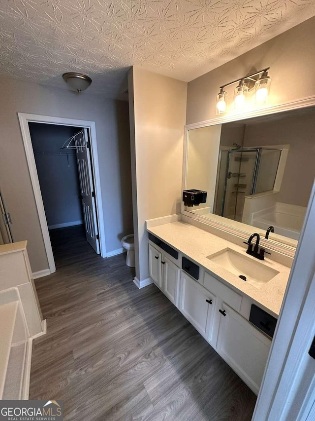 bathroom with vanity, hardwood / wood-style flooring, toilet, walk in shower, and a textured ceiling