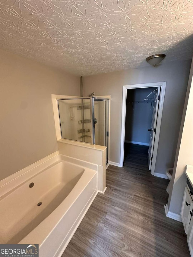 bathroom with vanity, independent shower and bath, a textured ceiling, and hardwood / wood-style flooring