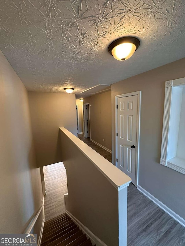 staircase featuring hardwood / wood-style floors and a textured ceiling