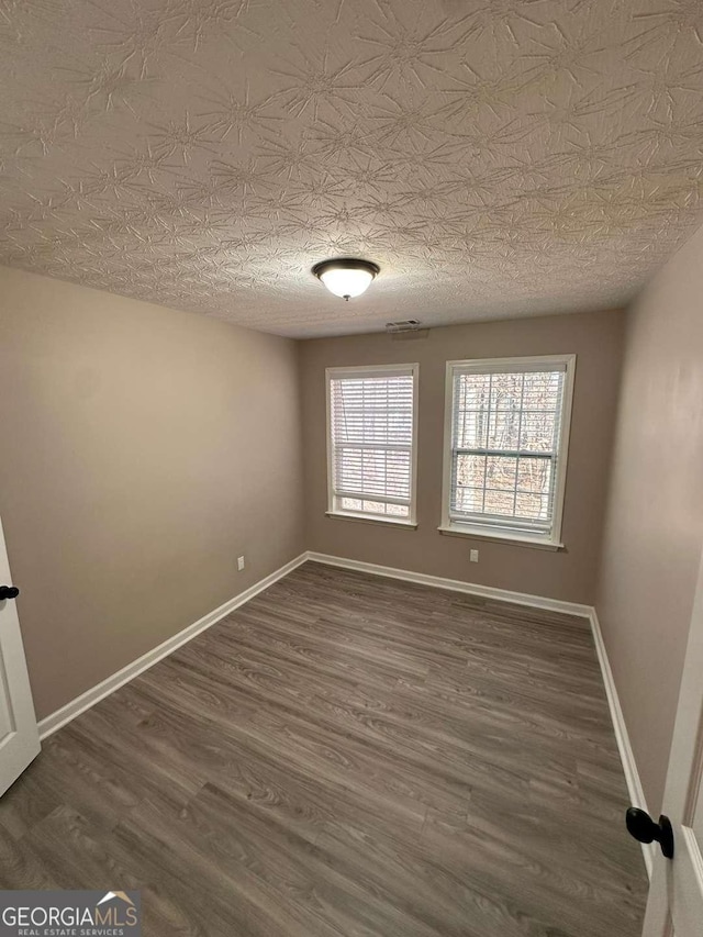 spare room featuring dark hardwood / wood-style floors and a textured ceiling