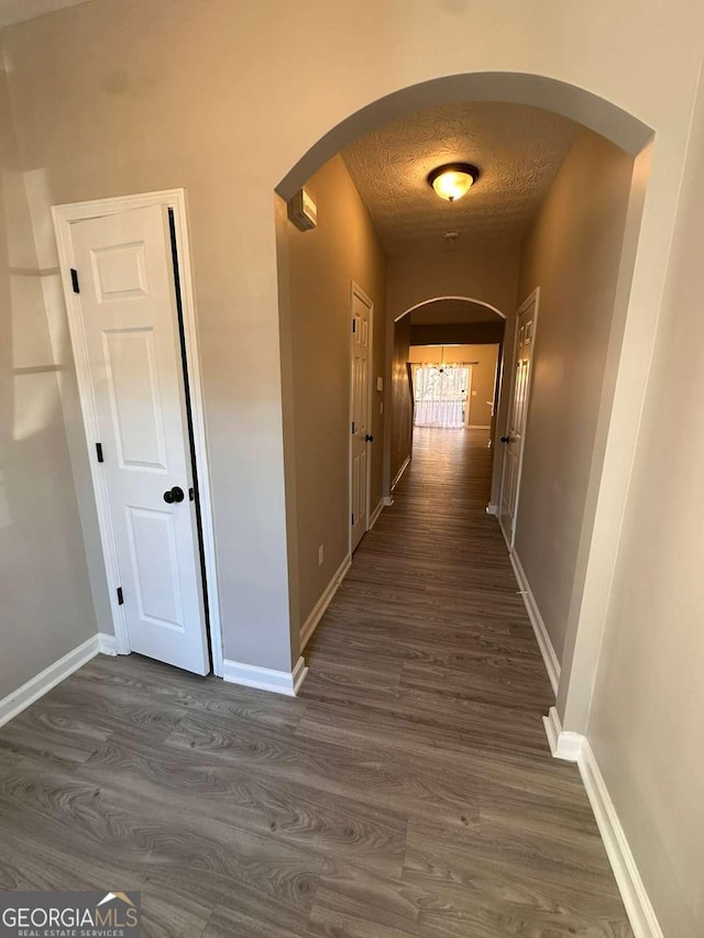 corridor with a textured ceiling and dark wood-type flooring