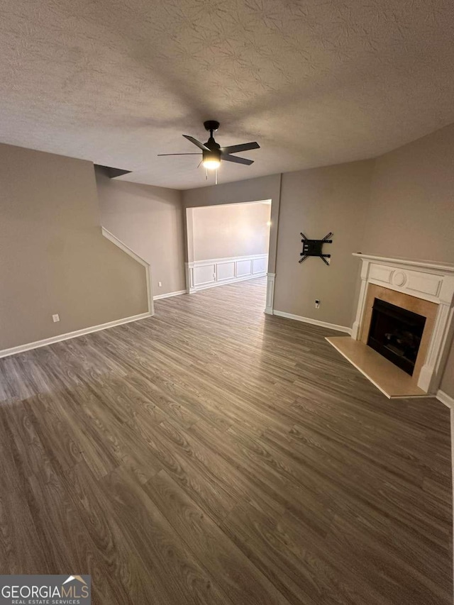 unfurnished living room featuring a textured ceiling, ceiling fan, and dark wood-type flooring