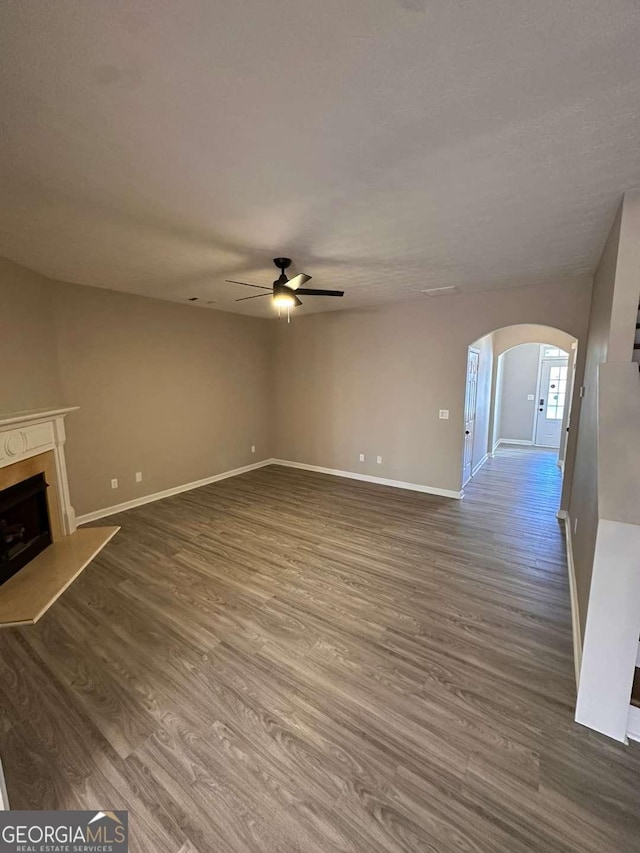 unfurnished living room with ceiling fan and dark wood-type flooring