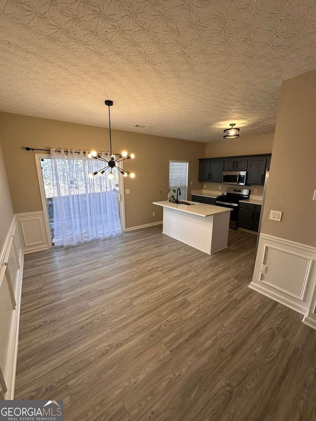 kitchen featuring sink, stainless steel appliances, dark hardwood / wood-style floors, a chandelier, and a center island with sink