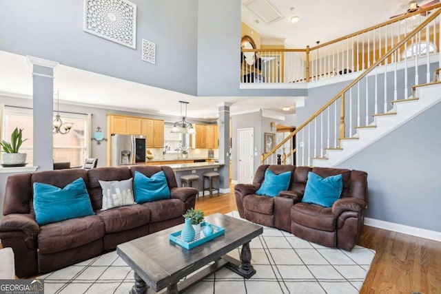 living room featuring light wood-type flooring, ornamental molding, and a high ceiling