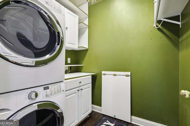 laundry room with dark hardwood / wood-style floors, cabinets, and stacked washer and clothes dryer