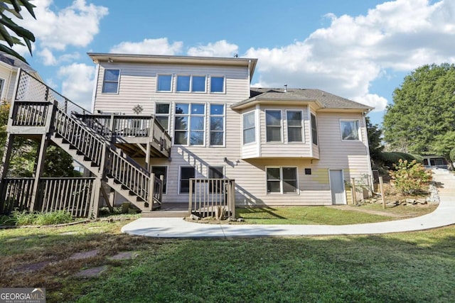 rear view of property featuring a wooden deck and a lawn