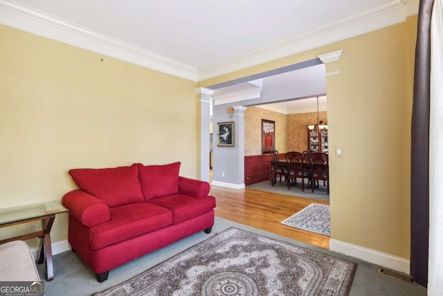 living room with decorative columns, crown molding, and wood-type flooring