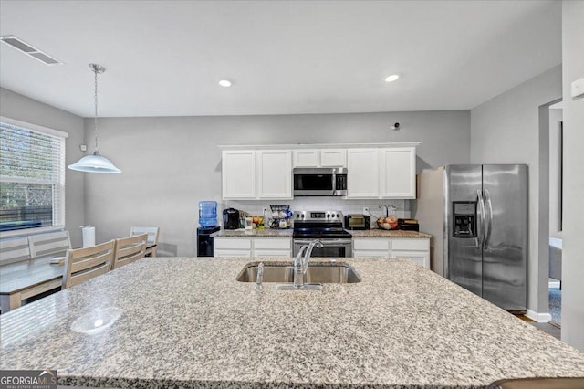 11945 Lovejoy Crossing Way, Hampton, GA 30228 - kitchen with appliances with stainless steel finishes, white cabinetry, decorative light fixtures, an island with sink, and light stone counters