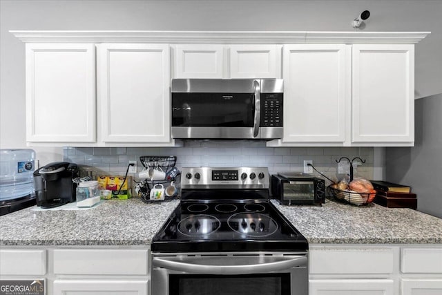 kitchen featuring decorative backsplash, light stone counters, white cabinetry, and appliances with stainless steel finishes