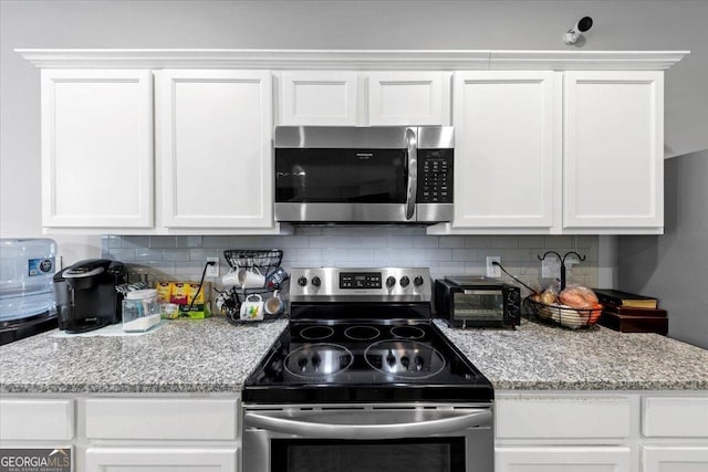 11945 Lovejoy Crossing Way, Hampton, GA 30228 - kitchen with appliances with stainless steel finishes, white cabinets, decorative backsplash, and light stone countertops