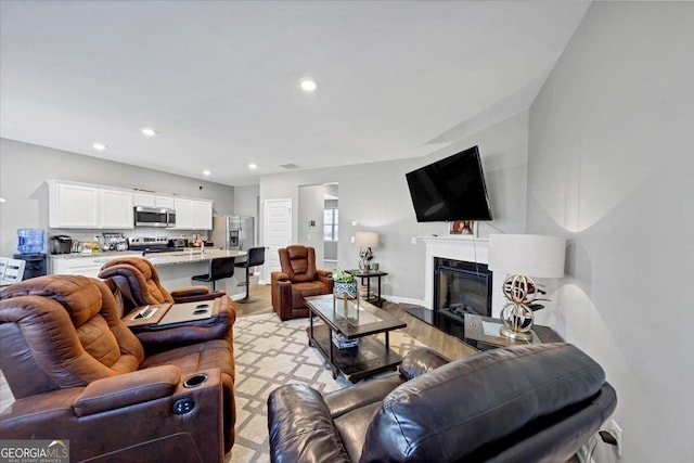 11945 Lovejoy Crossing Way, Hampton, GA 30228 - living room featuring a glass covered fireplace, light wood-style flooring, and recessed lighting