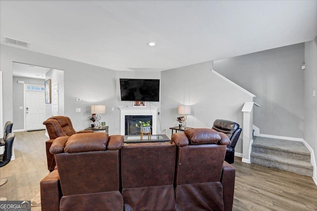 11945 Lovejoy Crossing Way, Hampton, GA 30228 - living room with stairway, wood finished floors, a glass covered fireplace, and recessed lighting