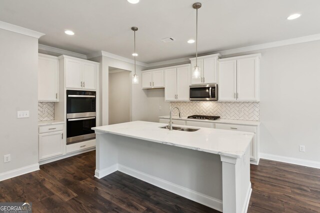 kitchen featuring pendant lighting, white cabinetry, sink, stainless steel appliances, and a center island with sink