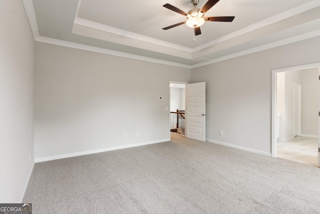 carpeted spare room featuring a tray ceiling, ornamental molding, and ceiling fan