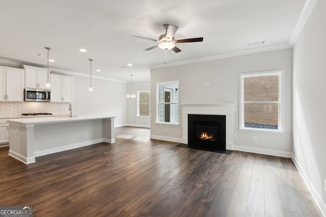 unfurnished living room with dark wood-type flooring, ornamental molding, and ceiling fan