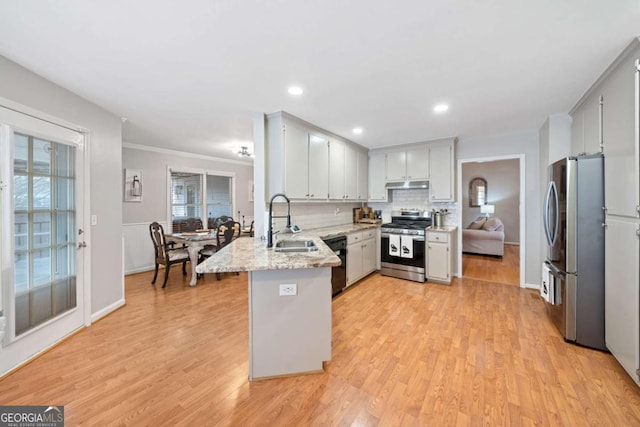 kitchen featuring sink, decorative backsplash, light hardwood / wood-style floors, kitchen peninsula, and stainless steel appliances