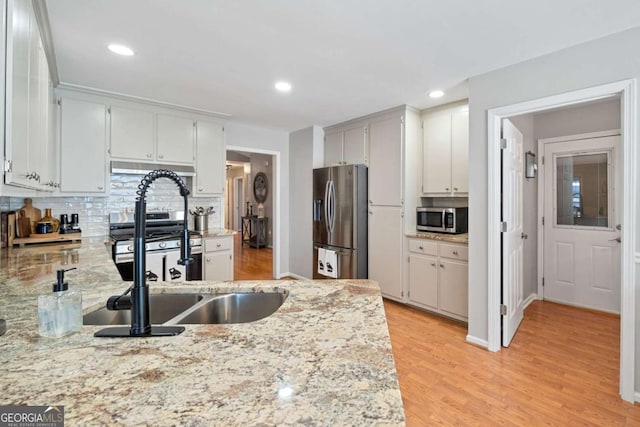 kitchen with decorative backsplash, light stone counters, and appliances with stainless steel finishes