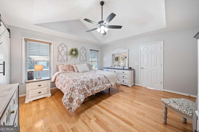 bedroom with ceiling fan, a raised ceiling, lofted ceiling, and light hardwood / wood-style flooring