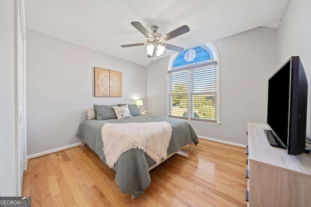 bedroom featuring ceiling fan, light hardwood / wood-style floors, and vaulted ceiling