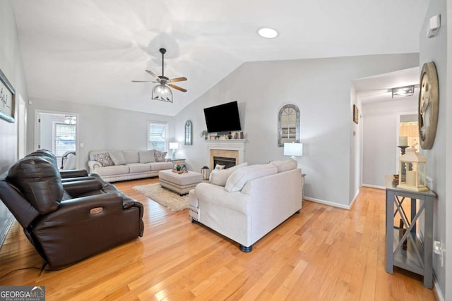 living room with ceiling fan, light hardwood / wood-style flooring, and vaulted ceiling