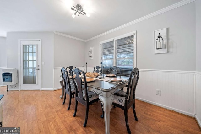 dining room with light wood-type flooring, heating unit, and ornamental molding