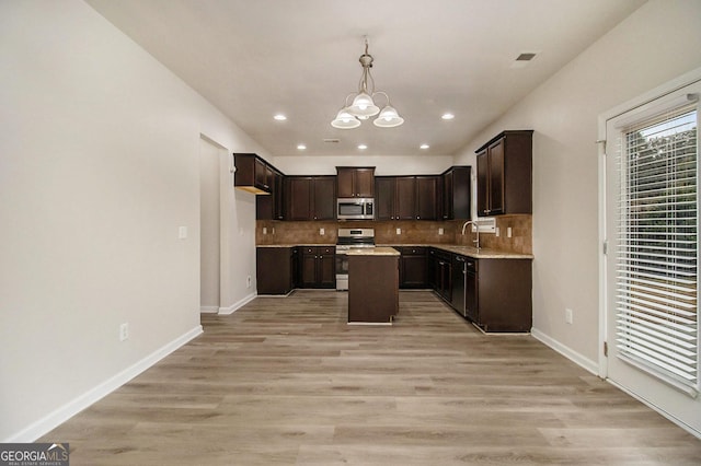 kitchen featuring hanging light fixtures, appliances with stainless steel finishes, a notable chandelier, a kitchen island, and dark brown cabinets