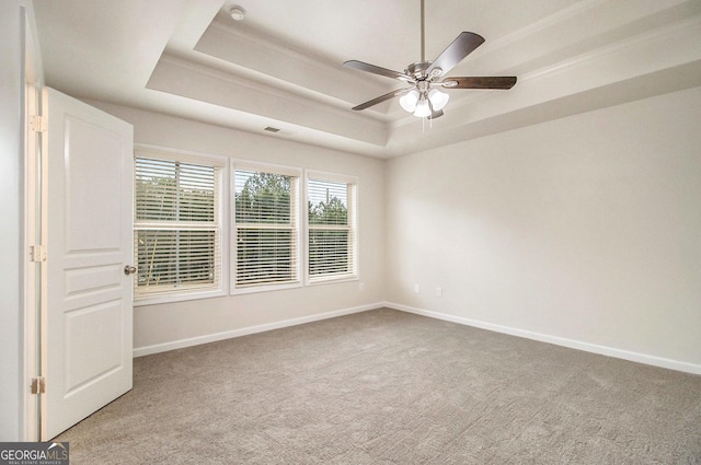 carpeted spare room featuring ceiling fan and a tray ceiling