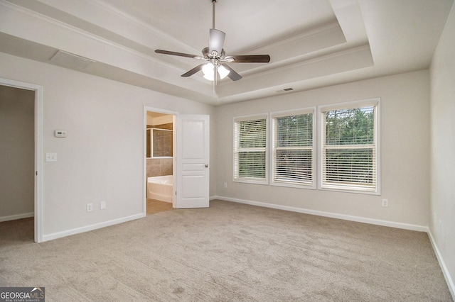 unfurnished bedroom featuring light carpet, ensuite bathroom, a raised ceiling, a walk in closet, and ceiling fan