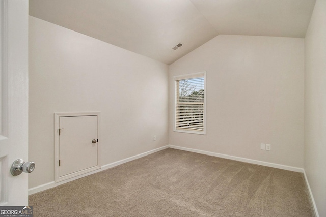 spare room with carpet flooring and vaulted ceiling