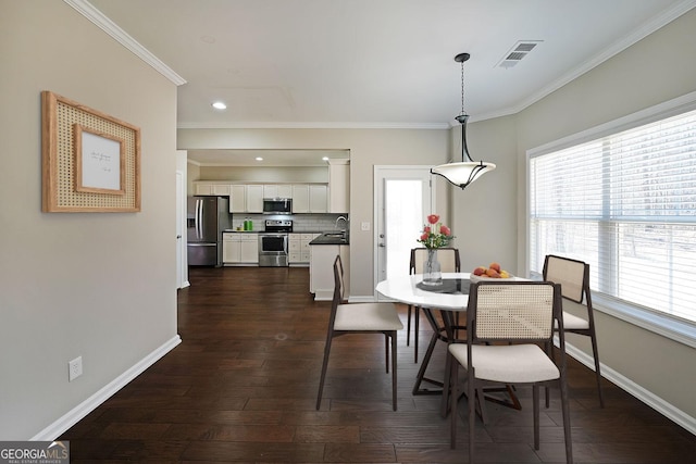 dining room featuring sink, dark hardwood / wood-style floors, and ornamental molding