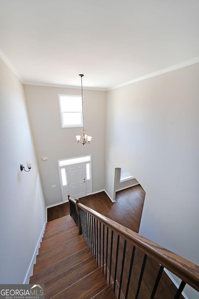 staircase featuring crown molding, hardwood / wood-style floors, and a chandelier