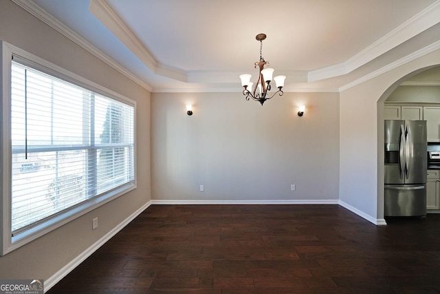 empty room with an inviting chandelier, dark hardwood / wood-style floors, a tray ceiling, and ornamental molding