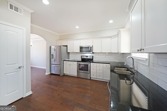 kitchen with appliances with stainless steel finishes, tasteful backsplash, sink, white cabinets, and dark hardwood / wood-style floors