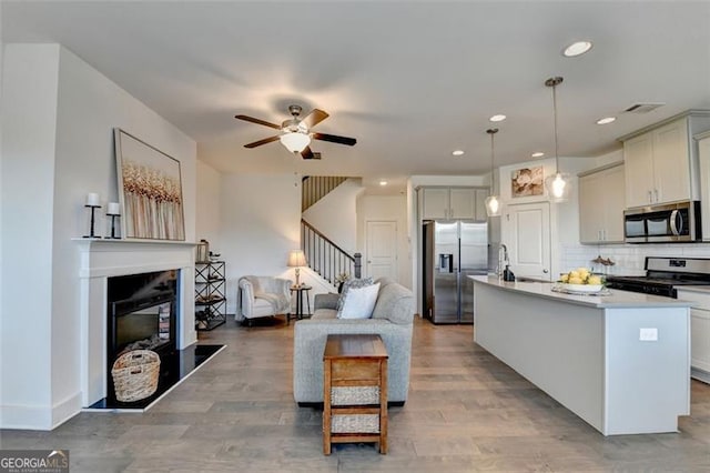 kitchen featuring pendant lighting, decorative backsplash, ceiling fan, appliances with stainless steel finishes, and a kitchen island