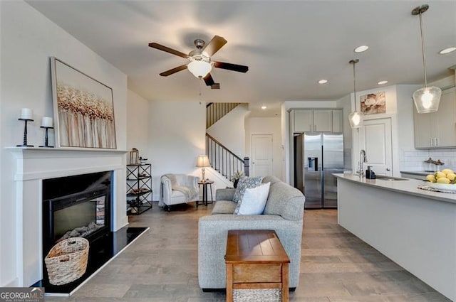 living room with wood-type flooring, ceiling fan, and sink