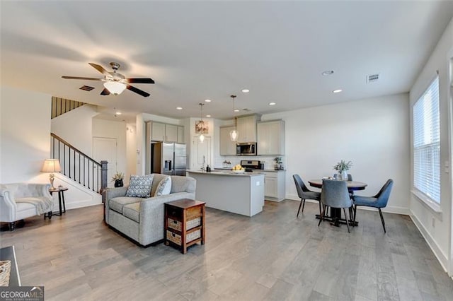 living room featuring ceiling fan, a wealth of natural light, and light hardwood / wood-style flooring