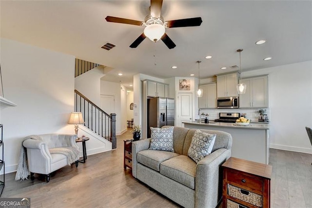 living room featuring hardwood / wood-style floors, ceiling fan, and sink