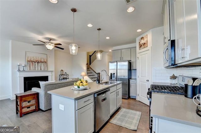 kitchen featuring hanging light fixtures, tasteful backsplash, a center island with sink, and stainless steel appliances