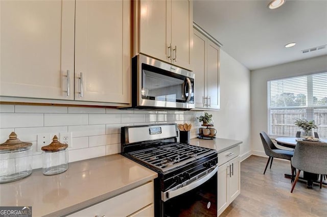 kitchen featuring light wood-type flooring, stainless steel appliances, and tasteful backsplash